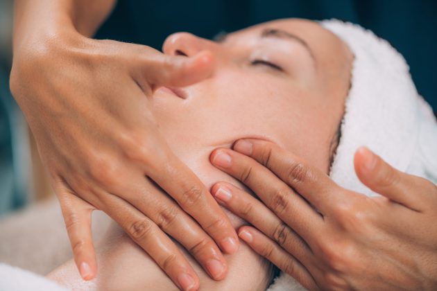 Face Fitness. Beautiful woman receiving face lifting massage in beauty salon.